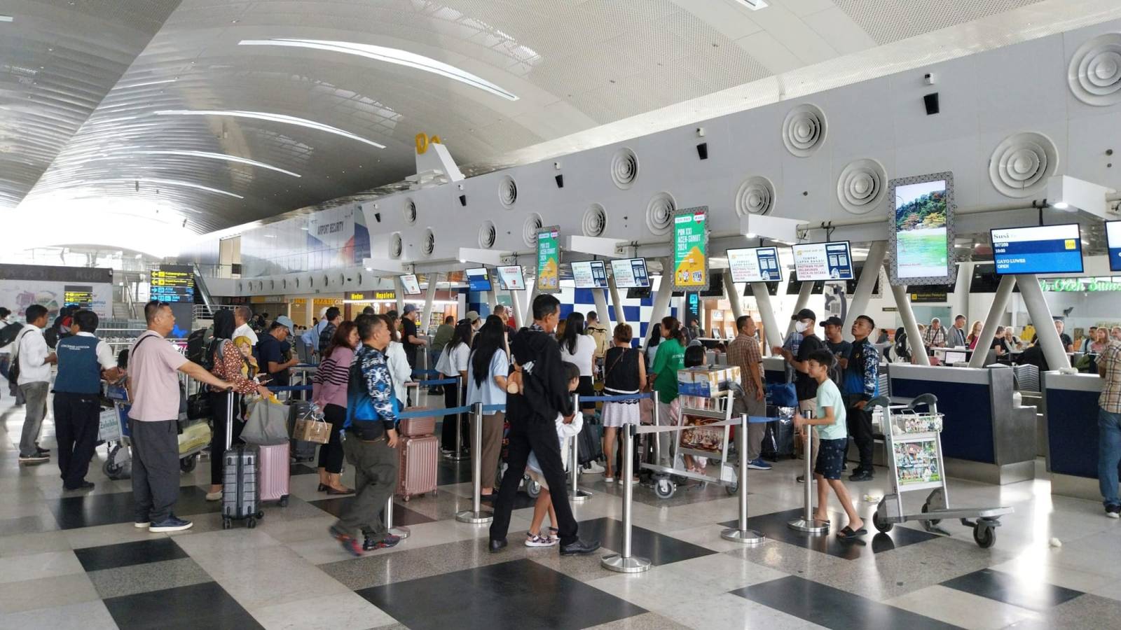 Rij reizigers met bagagekarren bij de incheckbalies van een luchthaven