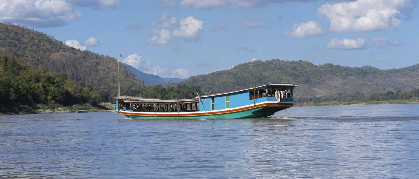 Slow boat op een brede rivier tussen groene heuvels