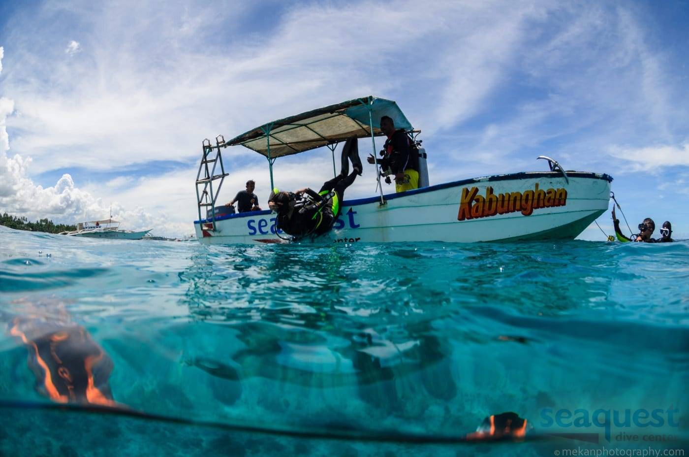 Duikers gaan vanaf de boot van Seaquest Dive Center het water in