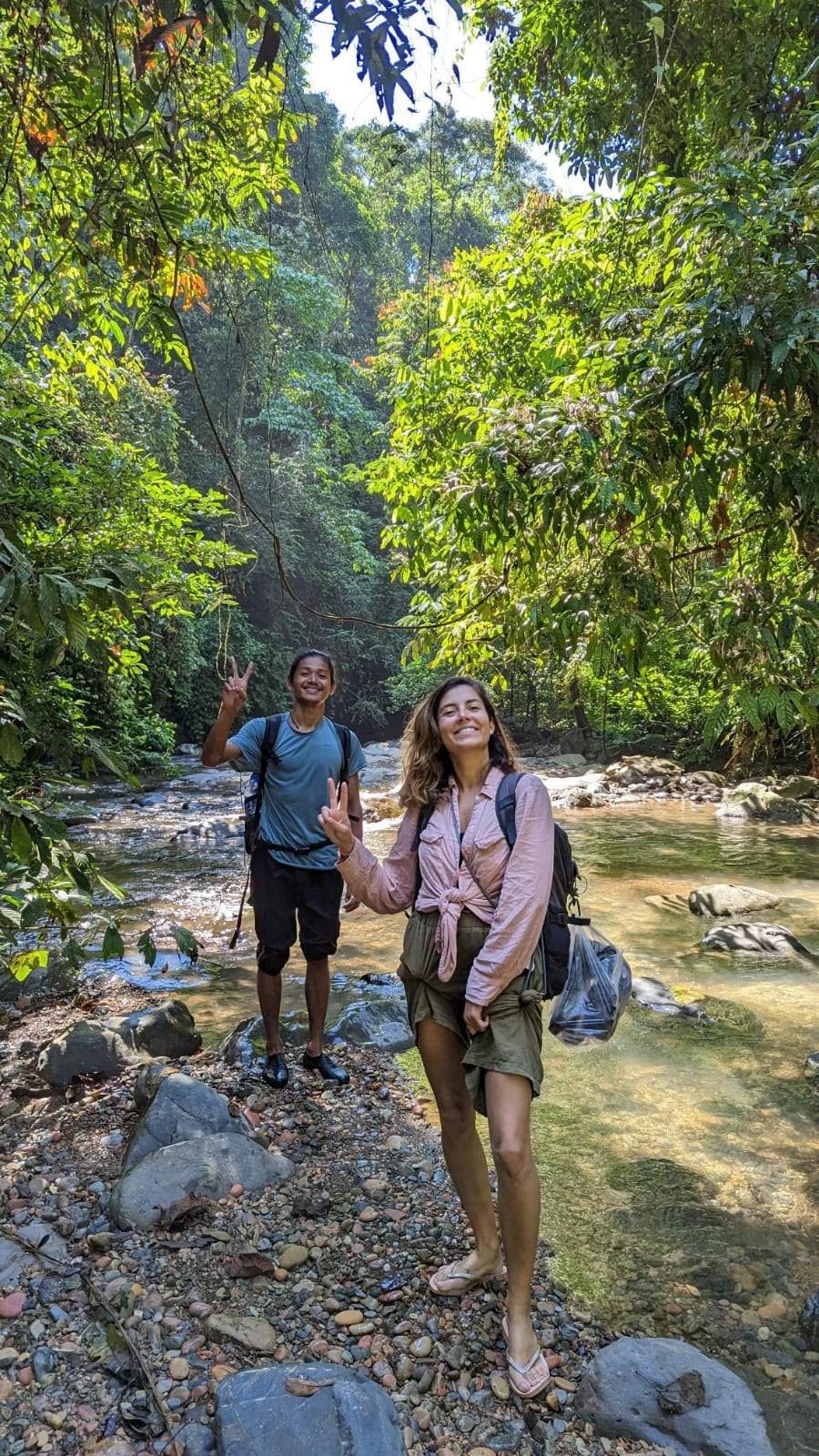 Twee trekkers op de stenen in een rivierbedding midden in de jungle