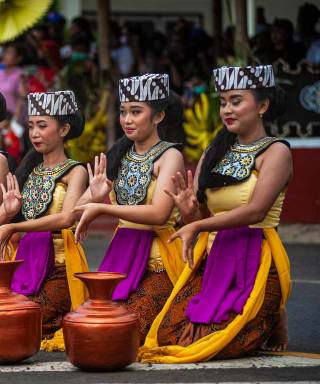 Rij danseressen in traditionele kostuums met koperen kruiken voor zich