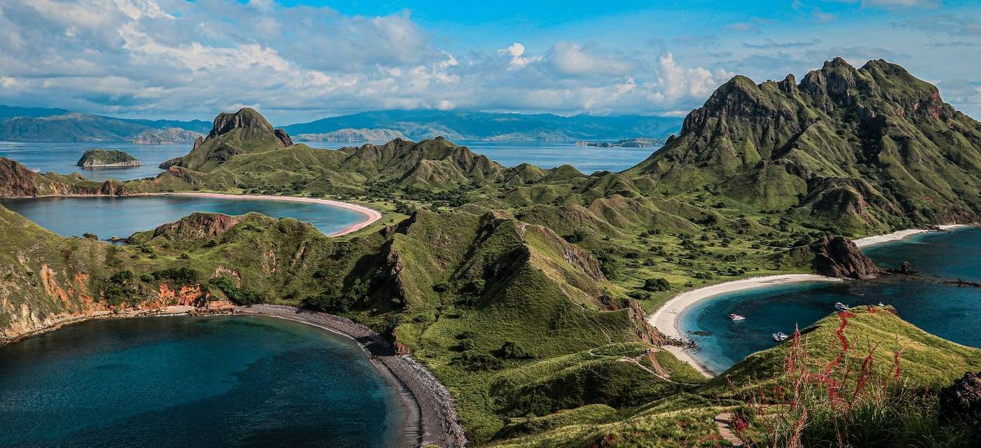 Groene heuvels en drie baaien met wit en roze zand op Padar