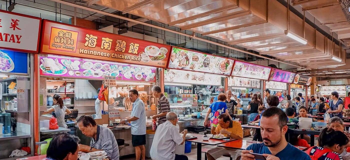 Drukte in een hawker centre met een kraam voor Hainanese chicken rice