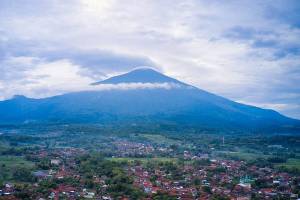 Vulkaan Salak met een wolkenkraag boven een stad op West-Java